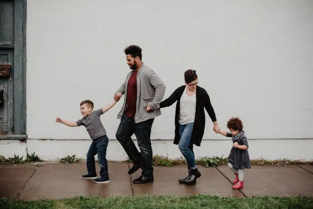 Free A joyful family walking together outdoors, holding hands in a playful and happy moment. Stock Photo