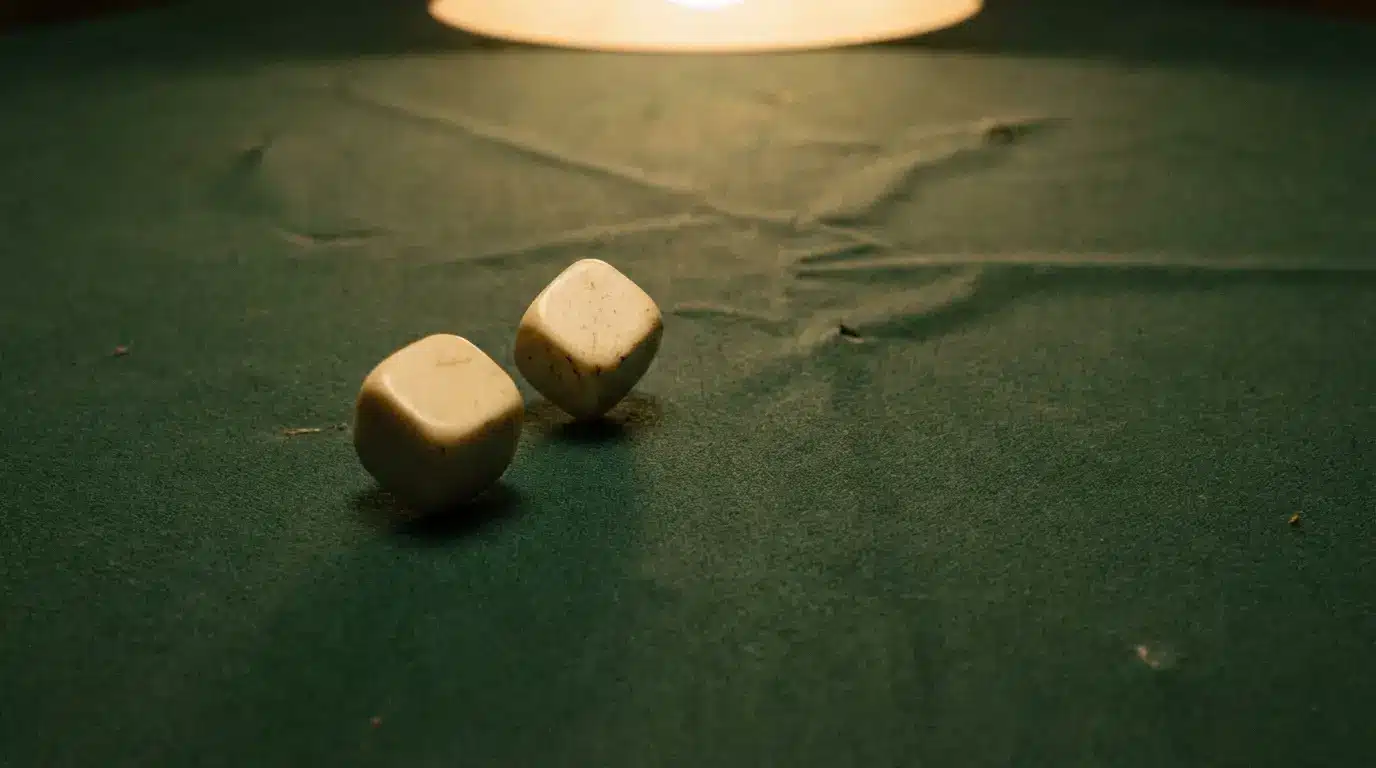 Two ivory dice resting on a green felt surface under warm light