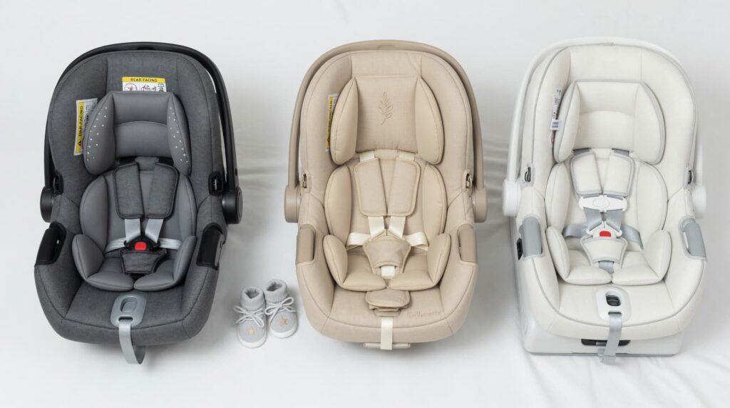Baby car seats comparison showing three infant car seats in gray, beige, and white with harness systems, arranged side by side on a neutral background.