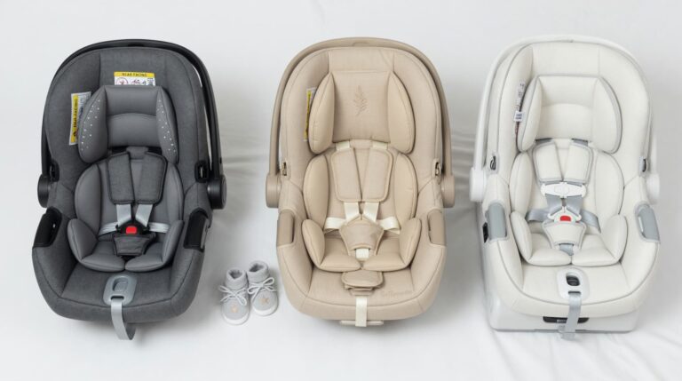 Baby car seats comparison showing three infant car seats in gray, beige, and white with harness systems, arranged side by side on a neutral background.