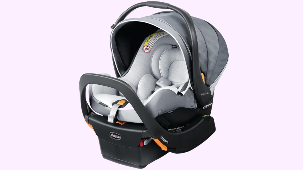 Gray infant car seat with canopy and carry handle, attached to a black base with safety labels and latch system, shown against a plain background
