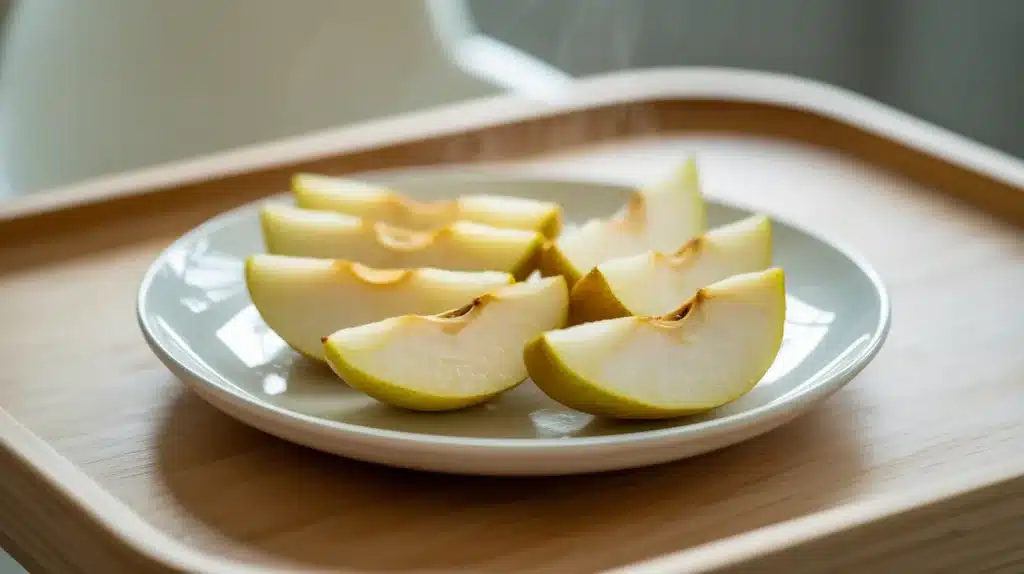 Soft-cooked pear slices arranged on a plate, showing tender fruit pieces suitable for baby-led weaning or easy eating