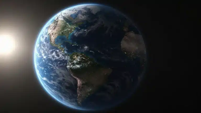 A view of planet Earth from space, showing glowing city lights on the night side and sunlight hitting the atmosphere.