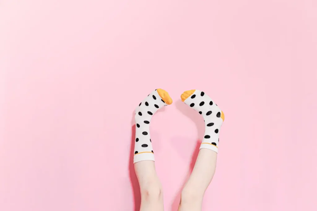 Polka dot socks on feet against a pink background